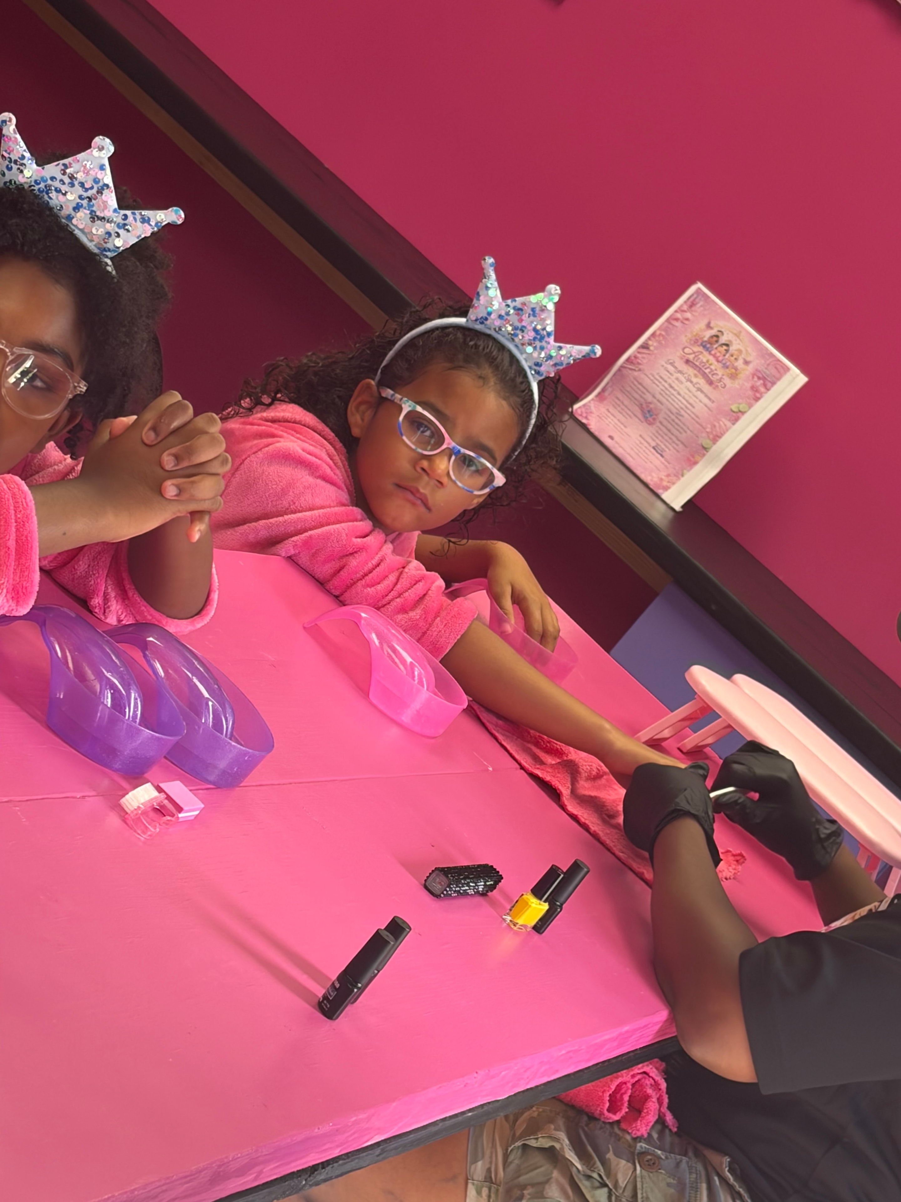 Little girl in pink robe and princess crown getting a manicure