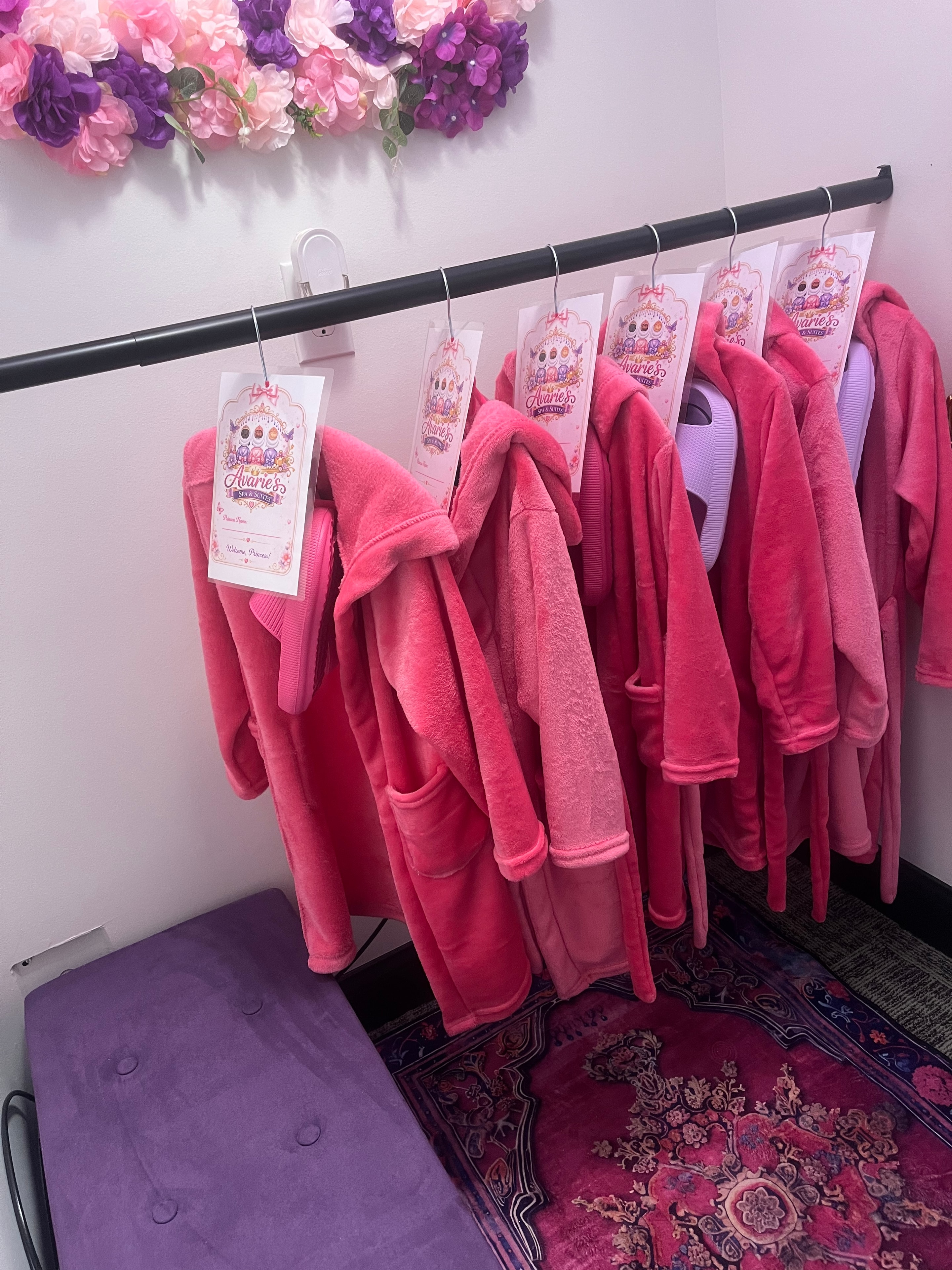 Pink spa robes with Avarie's Spa tags displayed on a rack